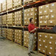 A man in red shirt standing next to boxes.